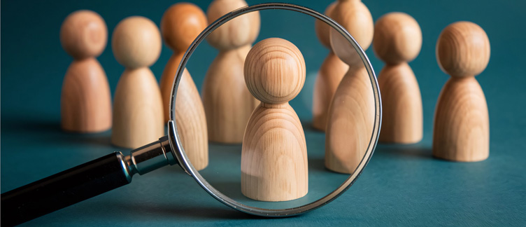 Holzspielfiguren stehen für einzelne Datensätze in der Adressdatenbank, eine Lupe hebt einen Datensatz hervor.